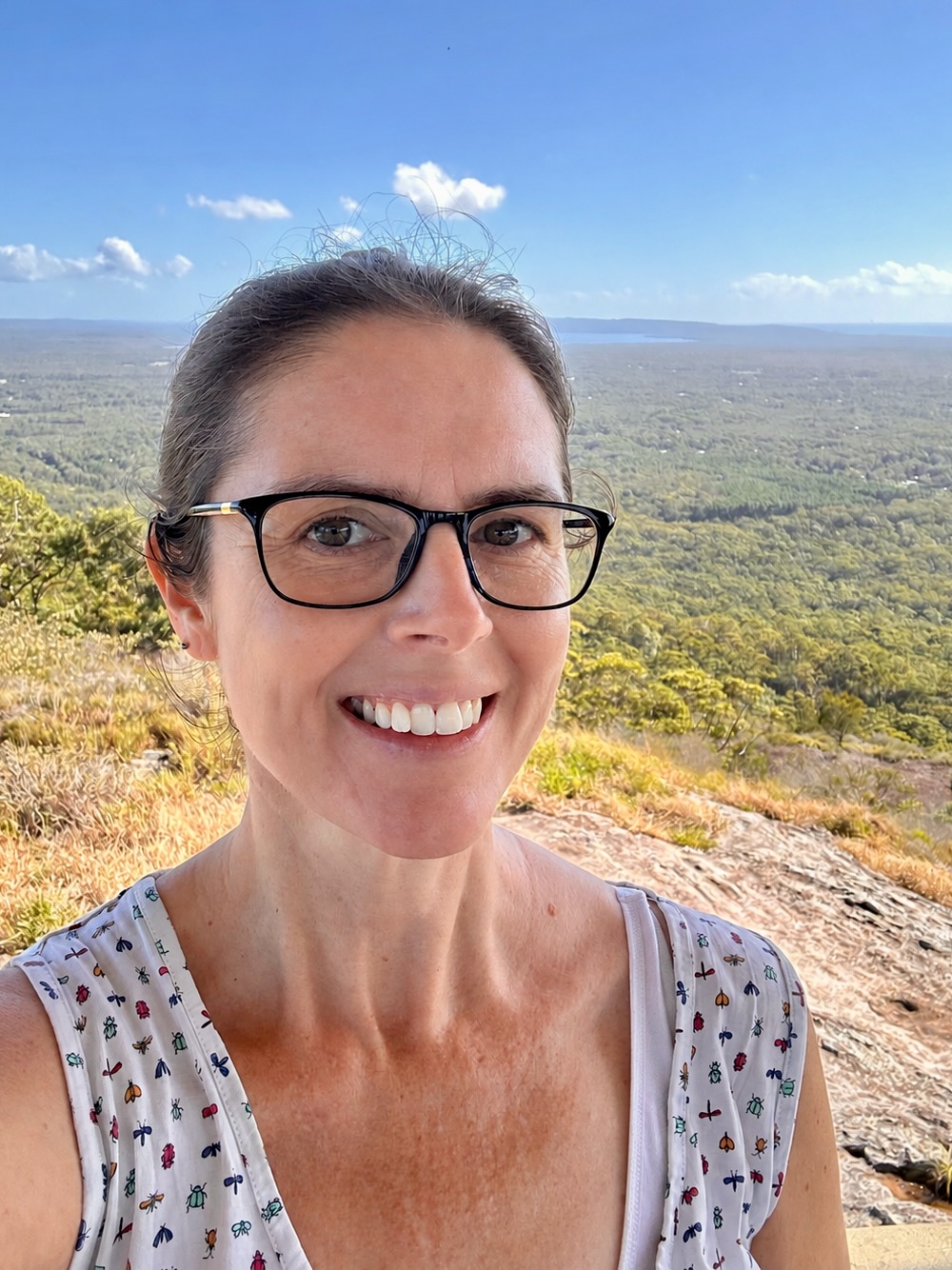 Sally smiling outdoors overlooking the coast