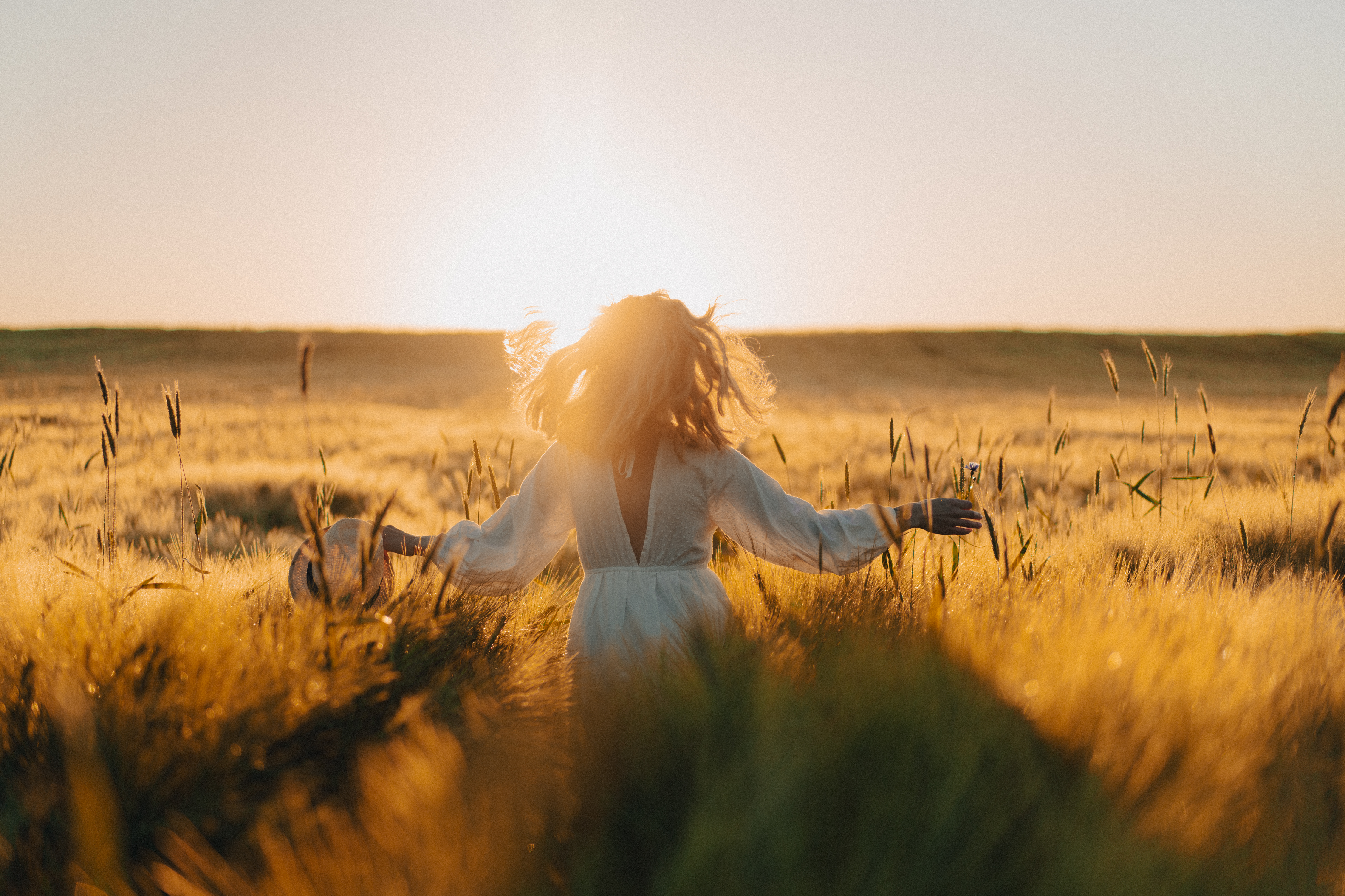 Woman walking through a field at golden hour